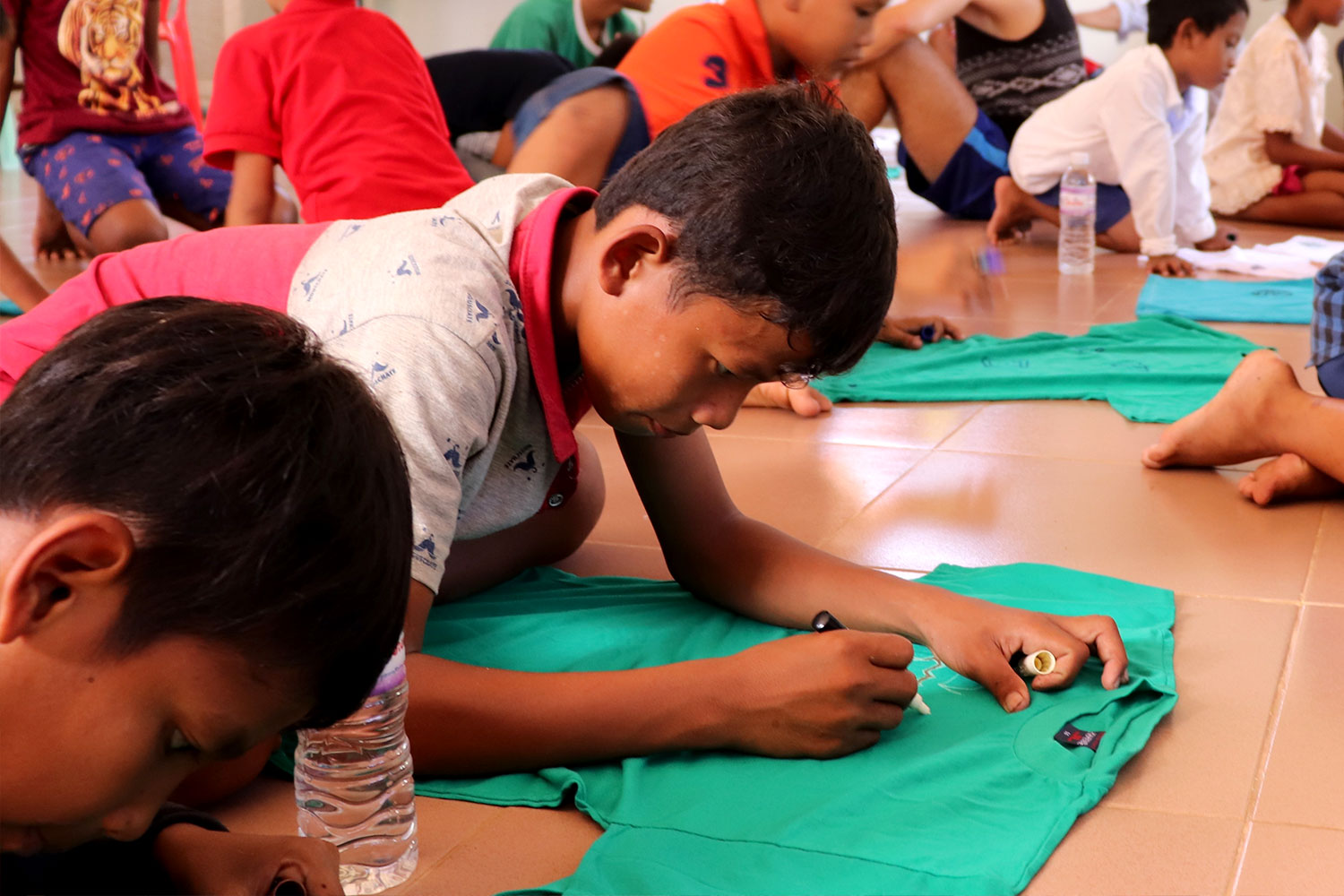Kinder beim beschriften von T-Shirts