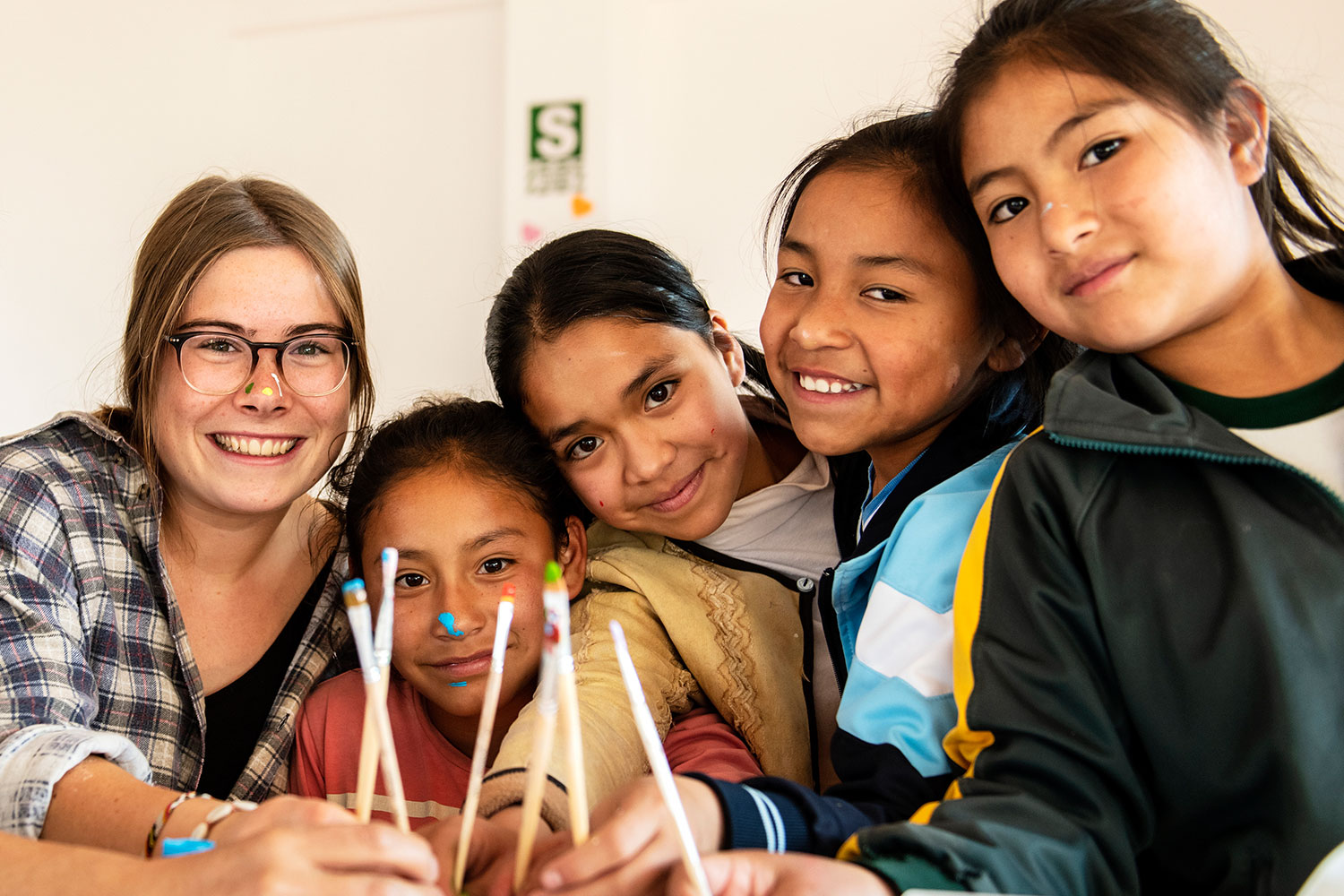 Freiwillige blickt mit vier Mädchen in Peru, Cajamarca in die Kamera