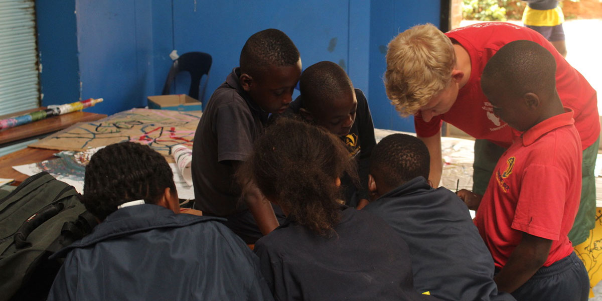 Freiwilliger hilft Jungen im Unterricht im Bildungsprojekt „Three2Six“ in Südafrika, Johannesburg