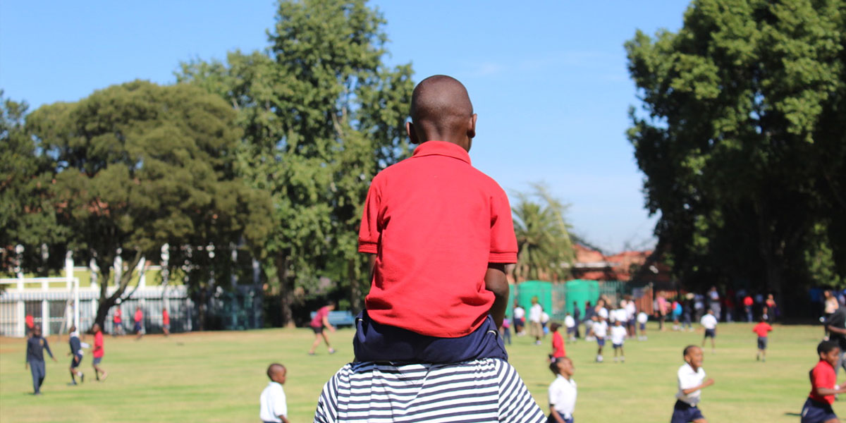 Freiwilliger trägt Jungen auf seinen Schultern in Südafrika, Johannesburg