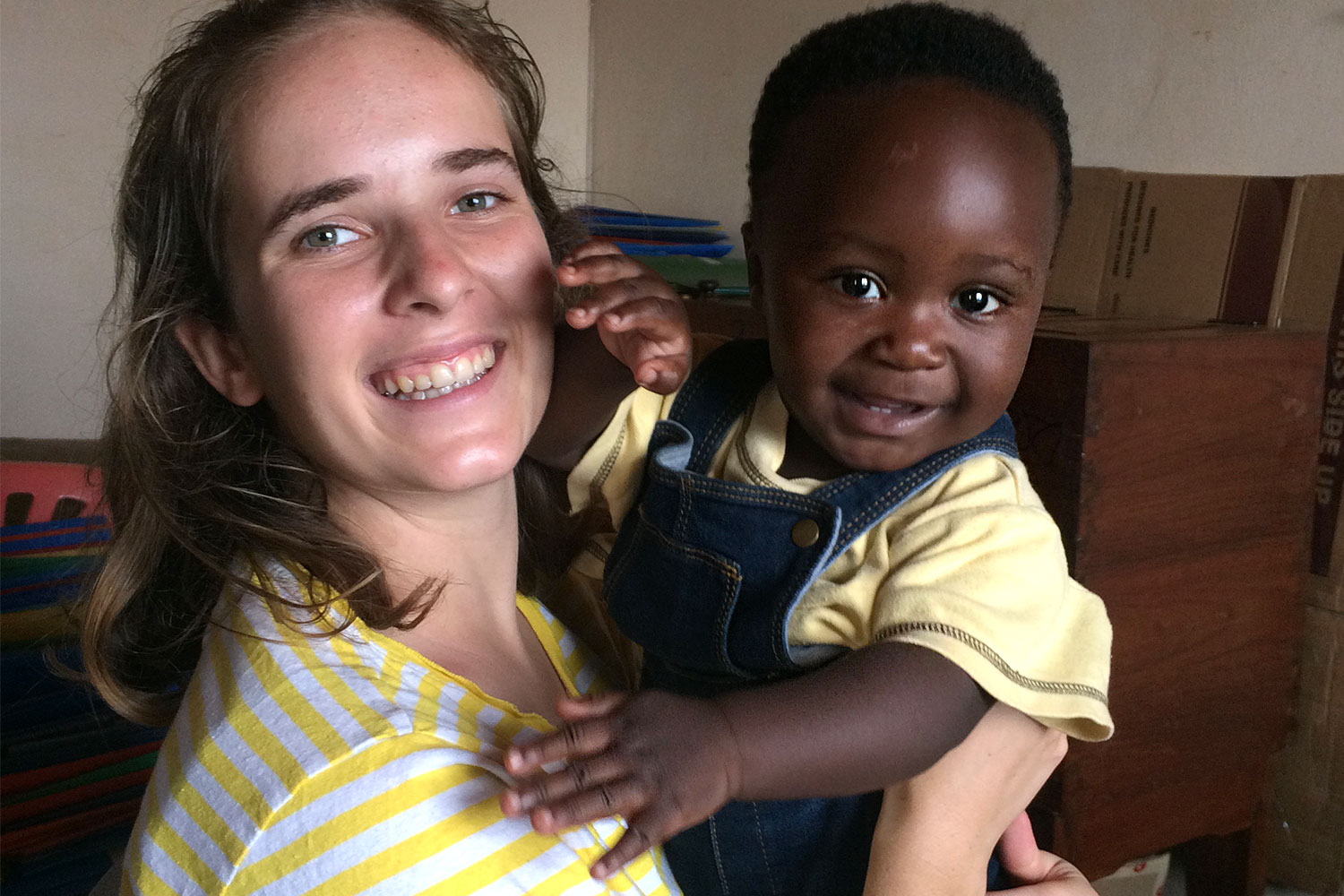 Freiwillige mit Kleinkind auf den Armen in Uganda, Mityana