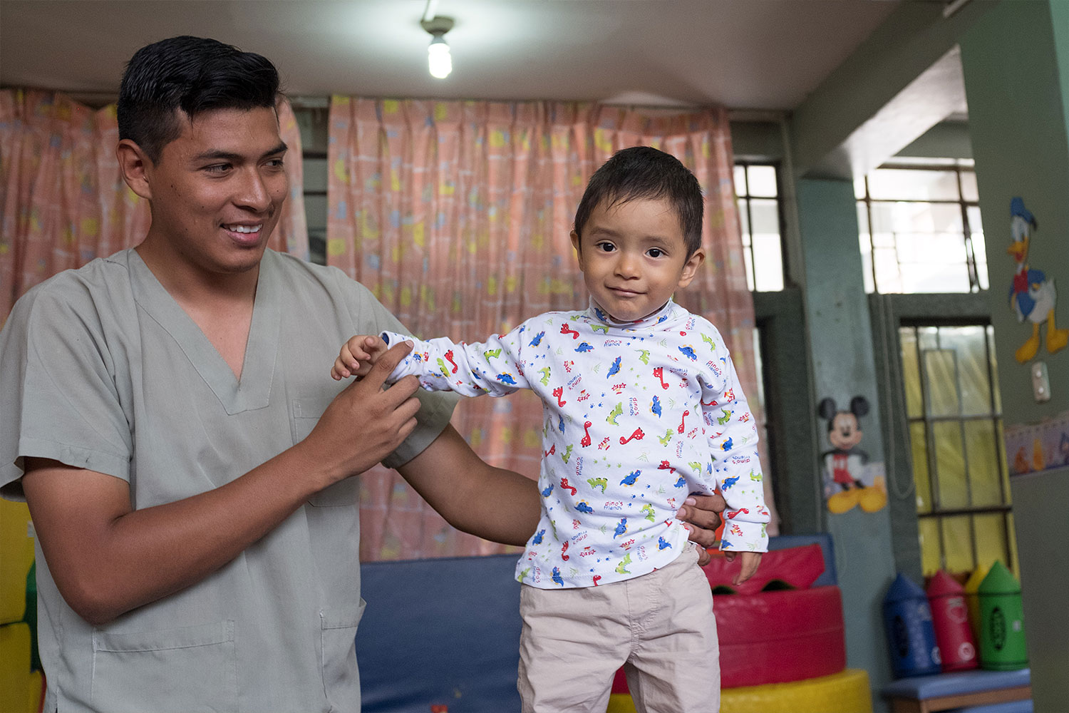 Mann in Peru, Lima stützt ein Kleinkind, dass in die Kamera lächelt
